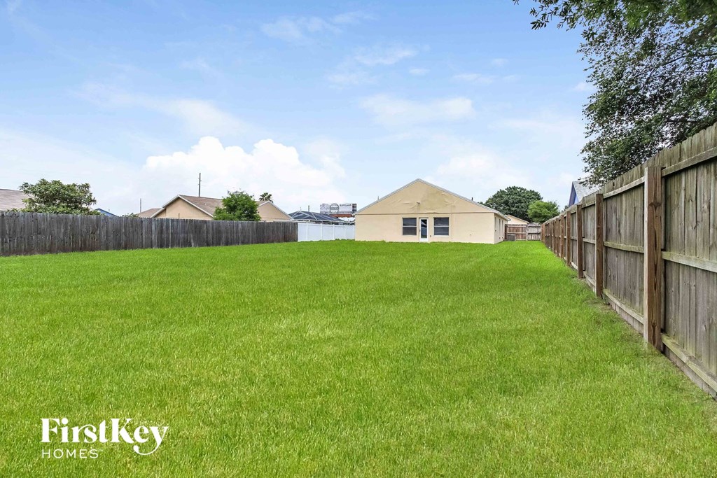 A grassy field with a wooden fence and a house in the distance.
