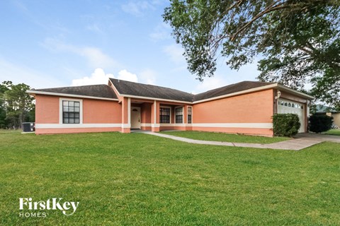 a brick house with a grass lawn and a tree