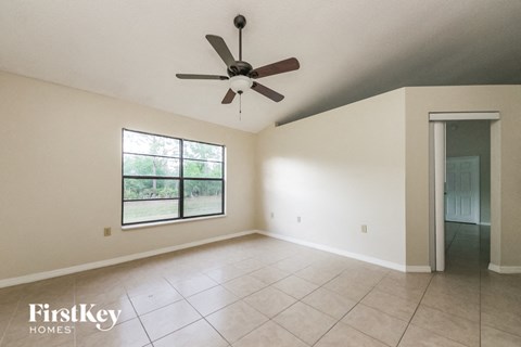 an empty living room with a ceiling fan and a large window