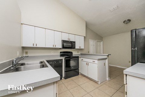 a kitchen with white cabinets and black appliances and a sink
