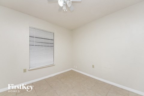 a spacious living room with a ceiling fan and a window