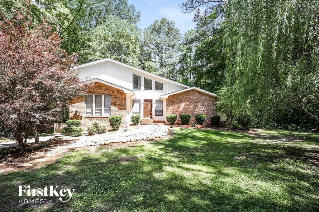 a small brick house with a lawn and trees