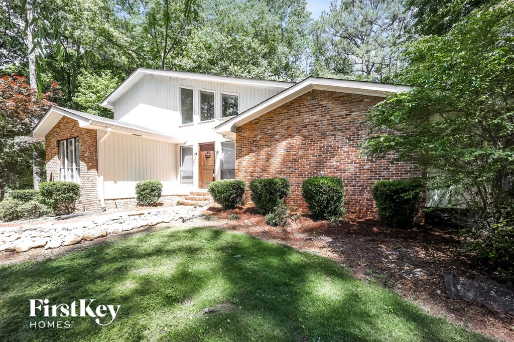 a small brick house with a lawn and a walkway