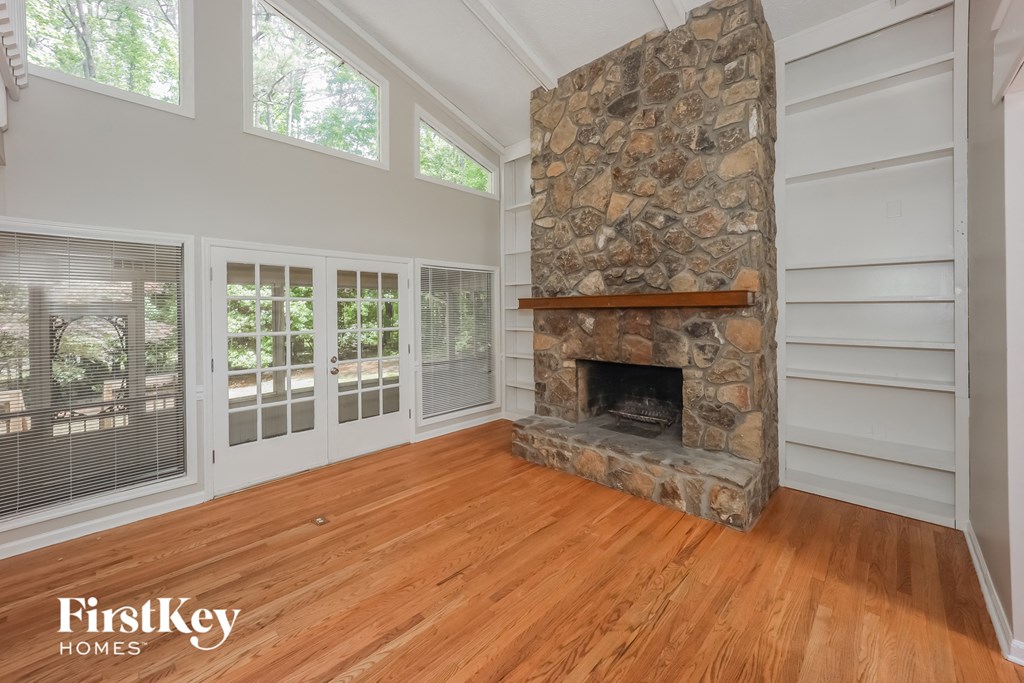 a living room with a stone fireplace and a wooden floor