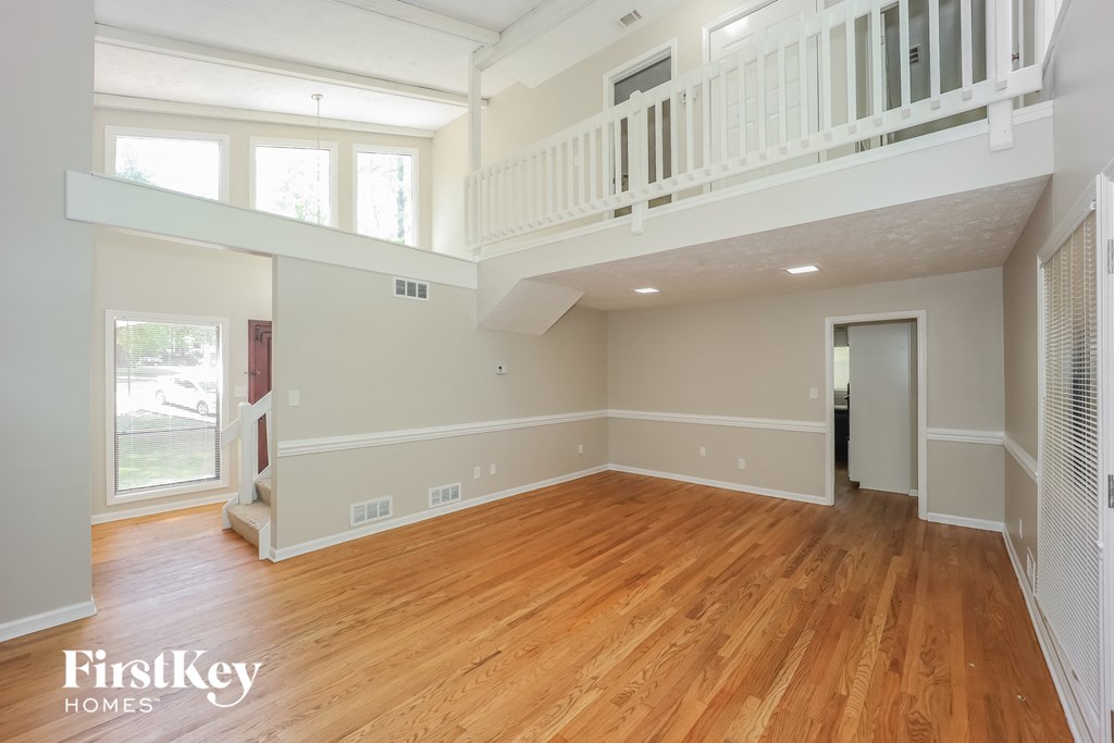 an empty living room with a hardwood floor and a balcony