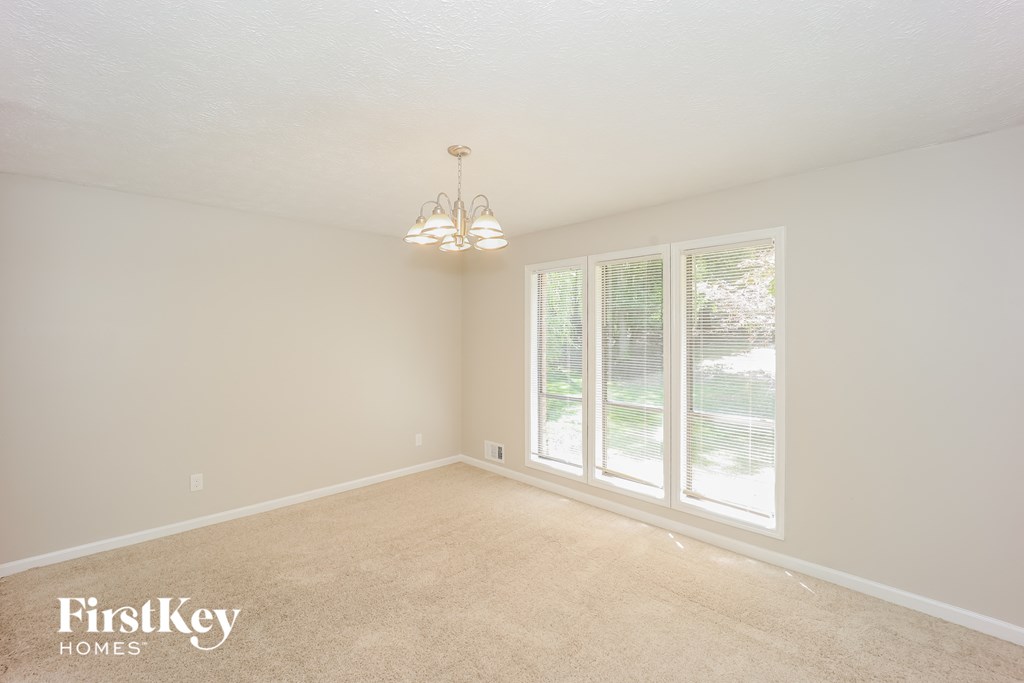 a spacious living room with a large window and a chandelier