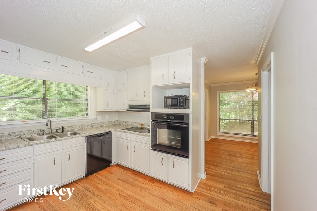 a kitchen with white cabinets and black appliances and a wood floor