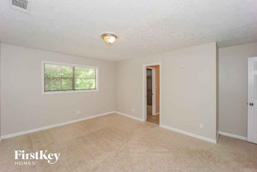 the living room of an empty house with a door to a hallway and a window