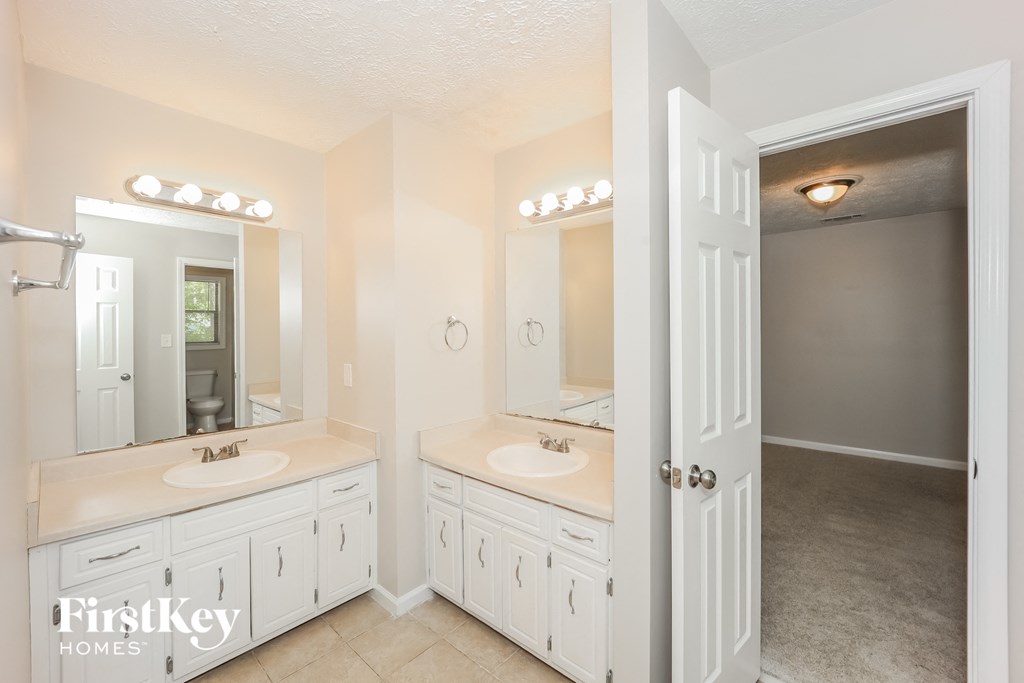 the master bathroom has two sinks and a large mirror