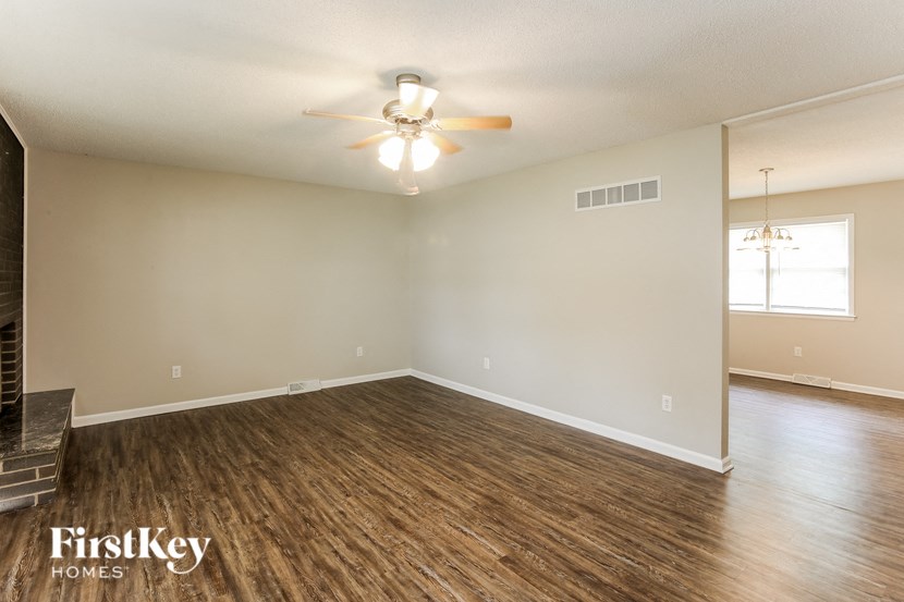 A spacious room with wooden flooring and a ceiling fan.