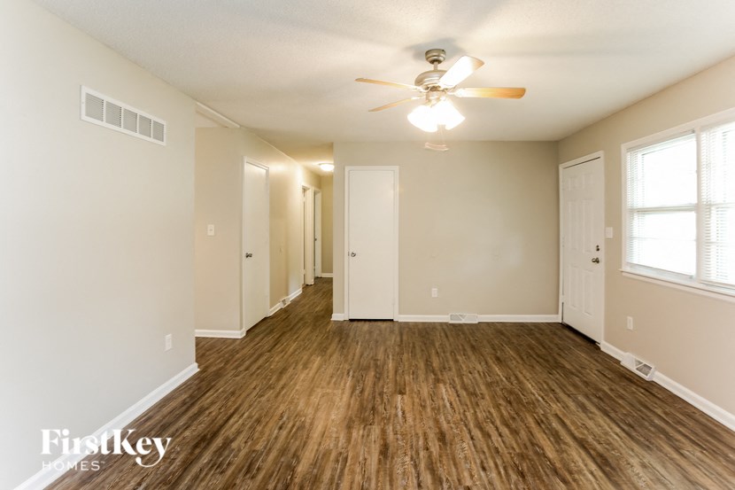 A spacious room with wooden floors and a ceiling fan.