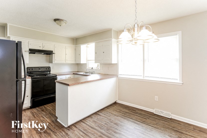 A kitchen with a black fridge and a white island.