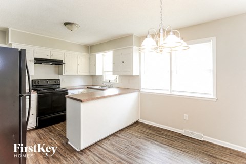 A kitchen with a black fridge and a white island.
