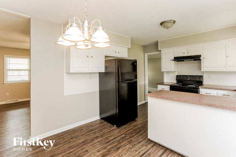 A kitchen with a black fridge and wooden floors.