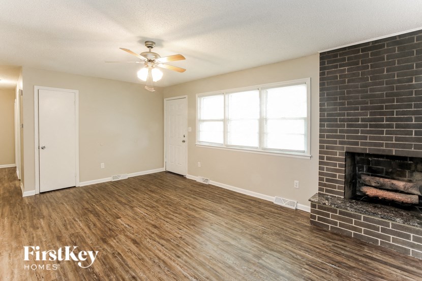 A room with a brick fireplace and wood flooring.