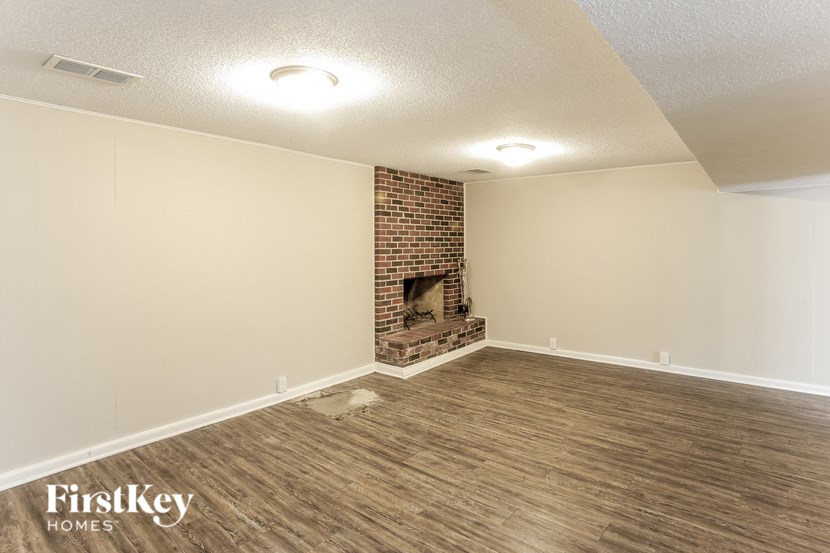 A room with a brick fireplace and wooden flooring.