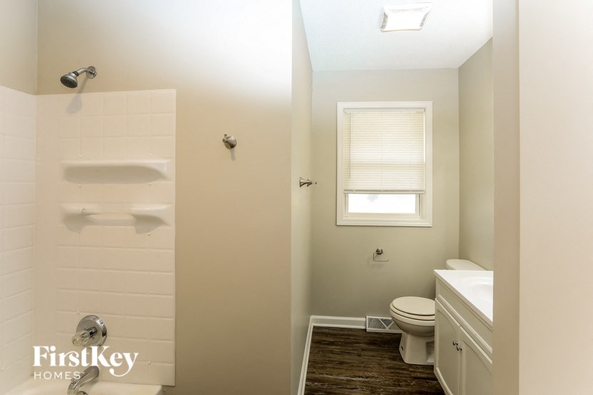 A white bathroom with a toilet, sink, and shower.