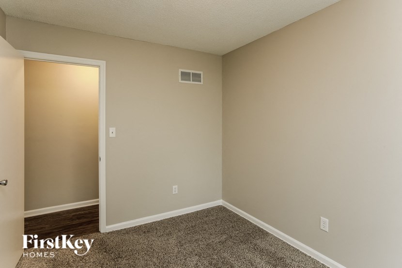 A carpeted room with a doorway leading to another room.