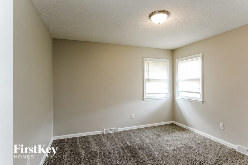 A room with a carpeted floor and two windows.