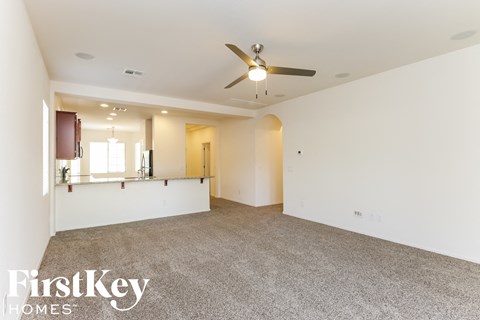 A spacious room with a ceiling fan and carpeted floor.