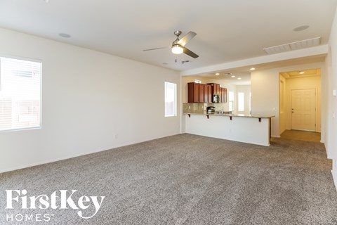 A spacious room with a carpeted floor and a ceiling fan.