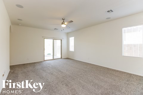 A spacious room with a carpeted floor and a ceiling fan.