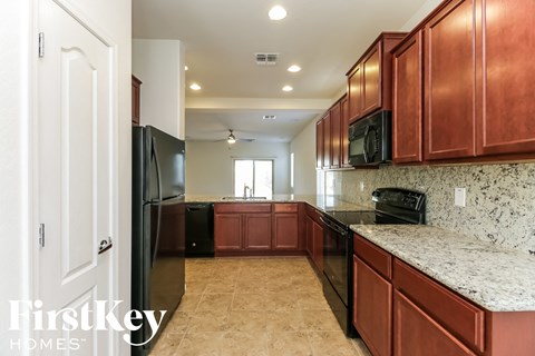 A kitchen with brown cabinets and a black fridge.