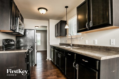 A kitchen with black cabinets and a FirstKey Homes logo.
