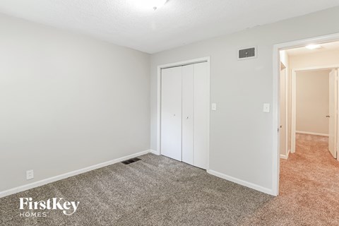 a bedroom with white walls and carpet and a closet
