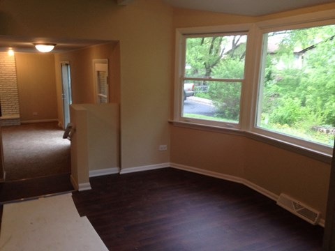 a dining room with a large window and a wooden floor