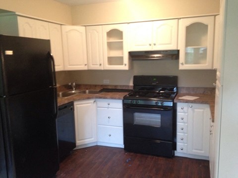 an empty kitchen with black appliances and white cabinets