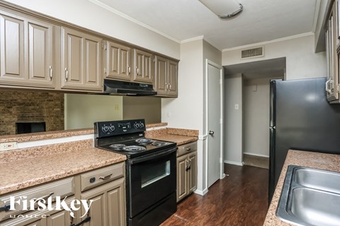 A kitchen with a black stove top oven and a stainless steel sink.