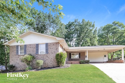 A house with a well-maintained lawn and trees in the background.
