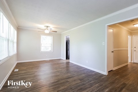A spacious room with wooden floors and a ceiling fan.