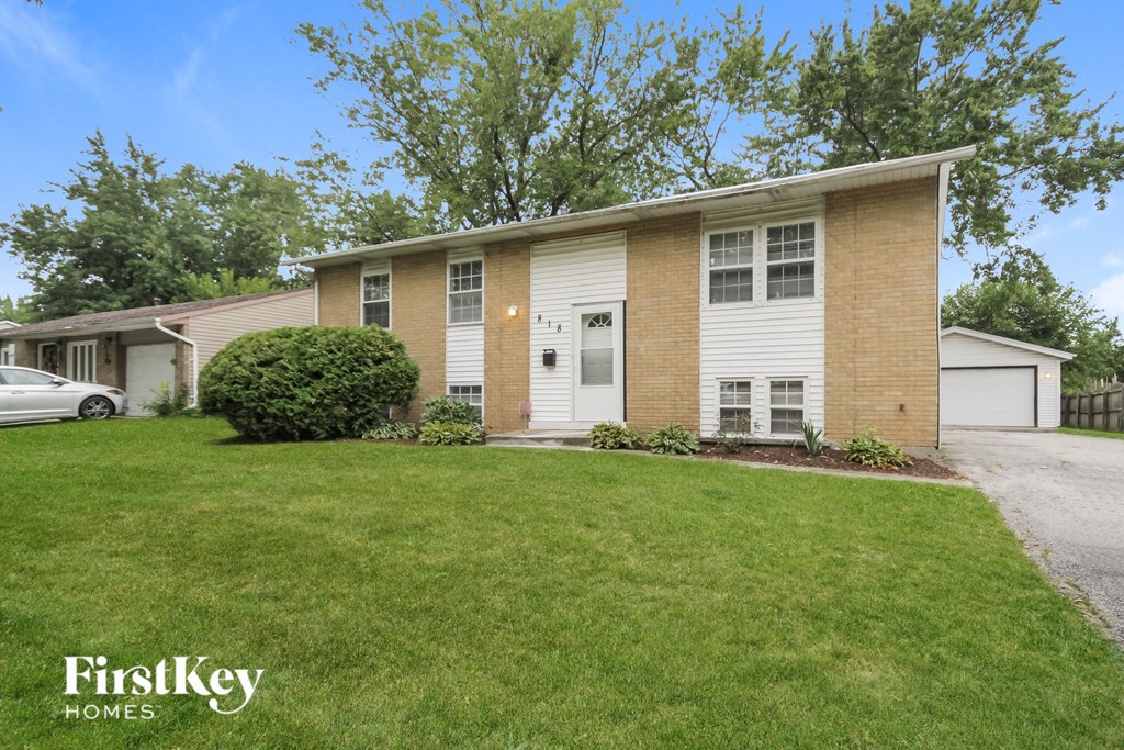 a white and brick house with a lawn and a car parked in front of it