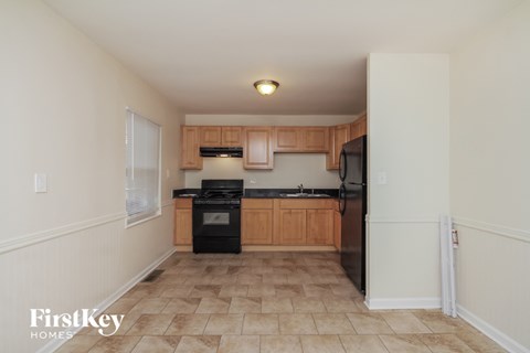 a kitchen with black appliances and wooden cabinets and tile flooring