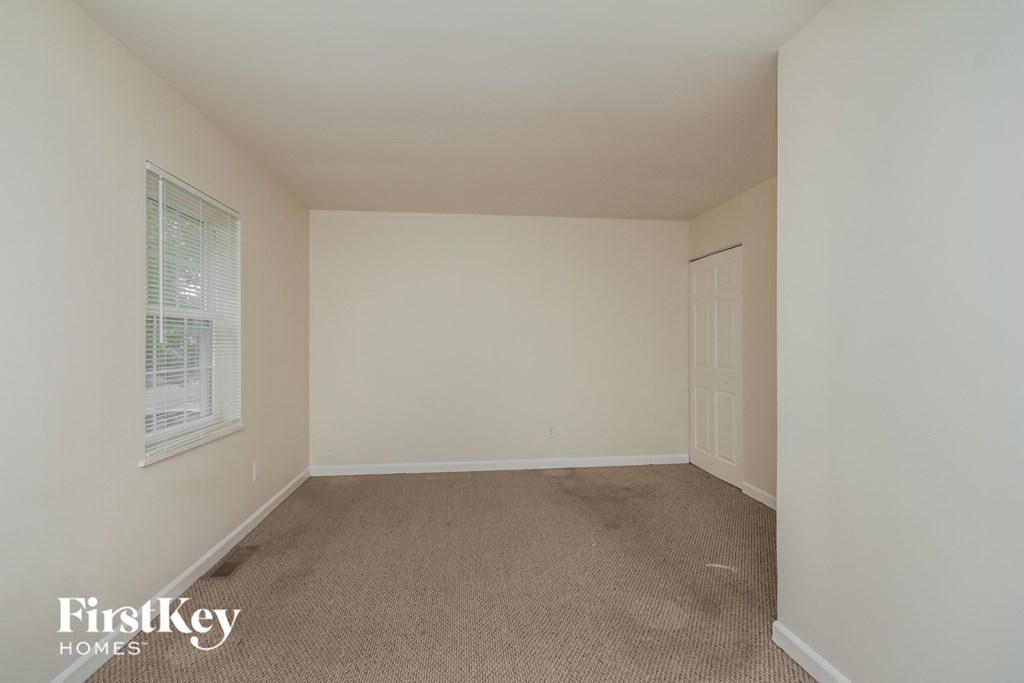 an empty bedroom with white walls and a window