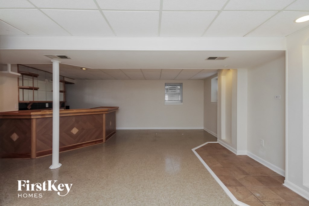 an empty basement with a kitchen and a bar
