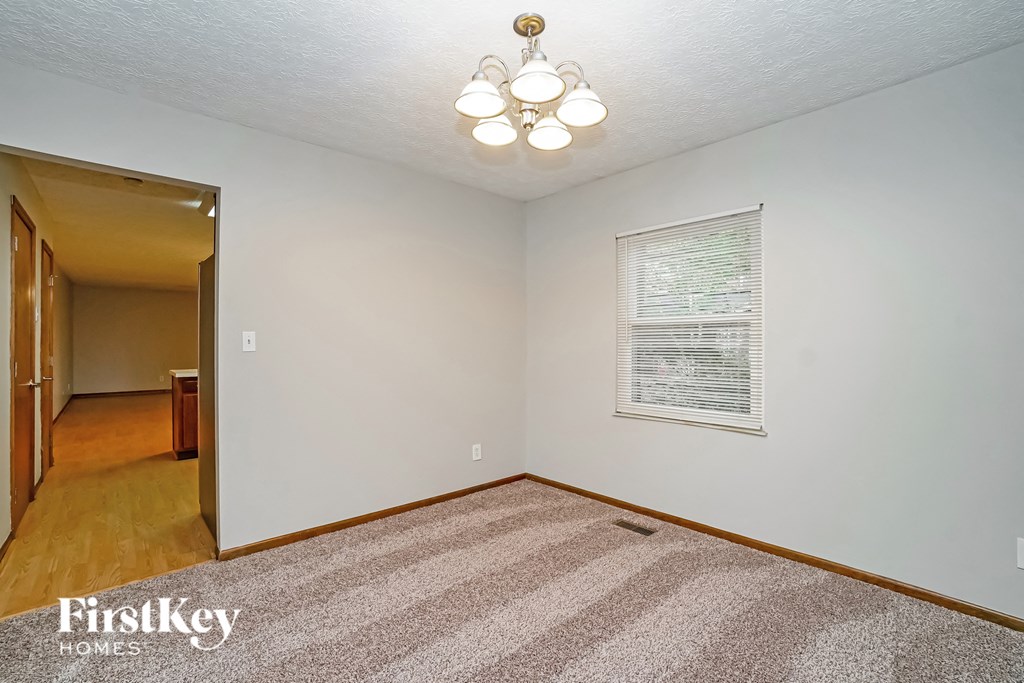 the living room and dining room of a house with white walls and a large window