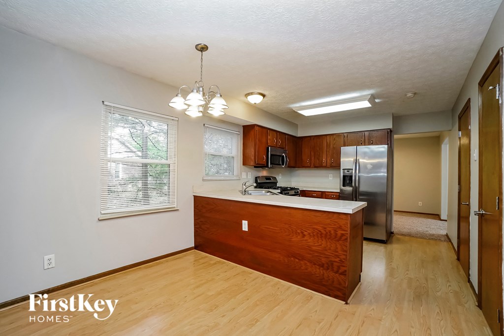 an empty kitchen with wooden cabinets and a stainless steel refrigerator