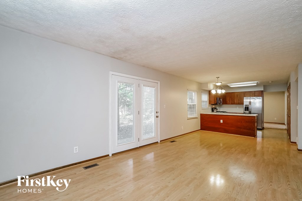 the living room and kitchen of an empty house with a wood floor