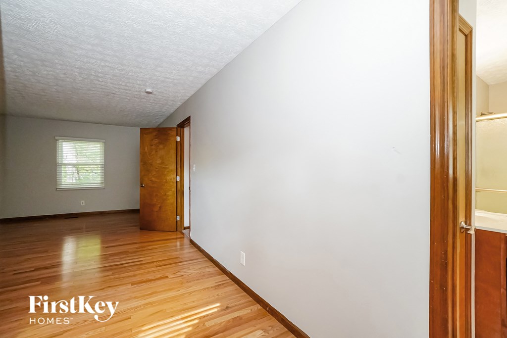 an empty room with a white wall and wooden floors
