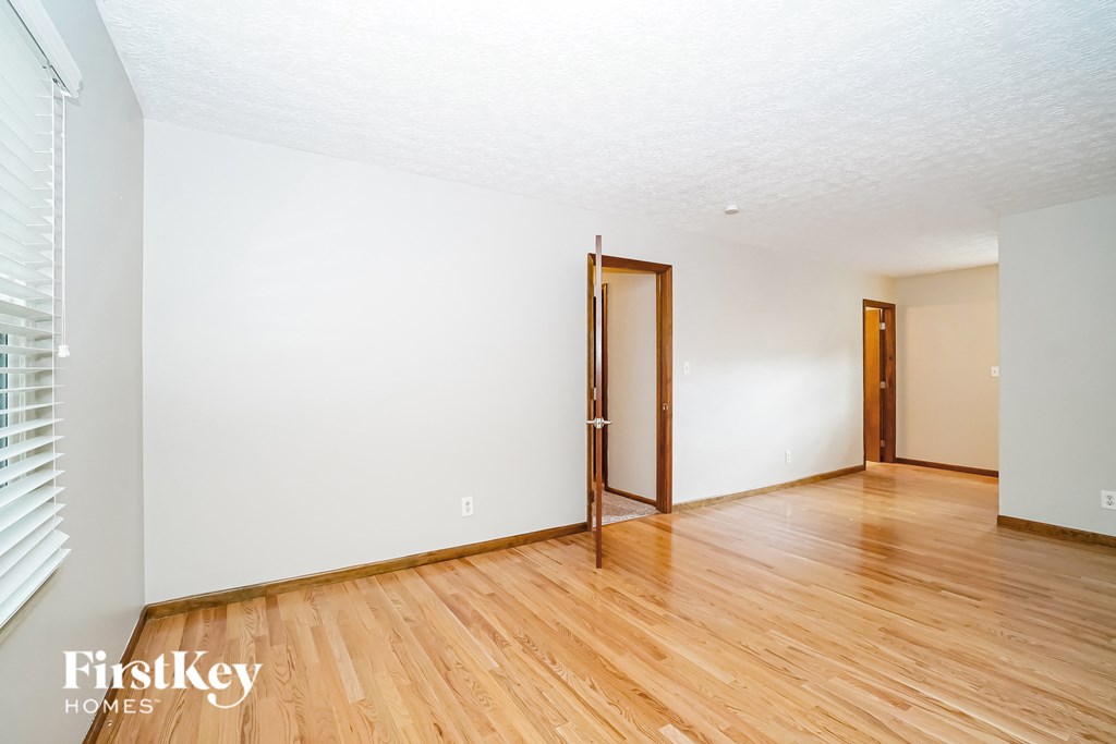 the living room of a house with wood floors and white walls