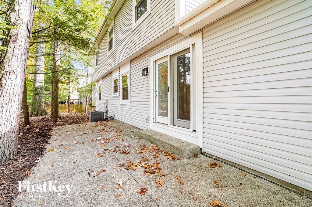 a side view of a white house with a driveway and trees