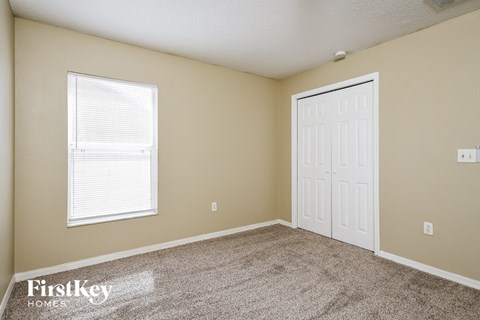 a bedroom with carpet and a white door and a window