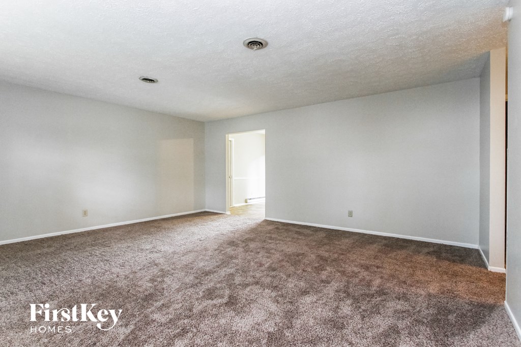 an empty living room with carpet and white walls