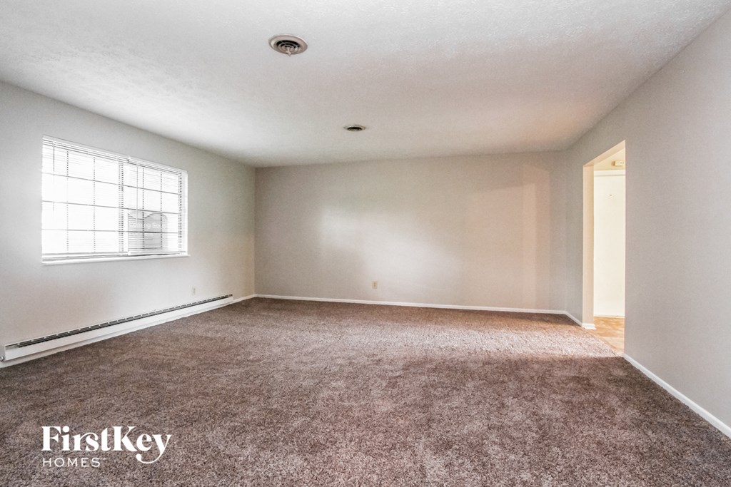 an empty living room with carpet and a window
