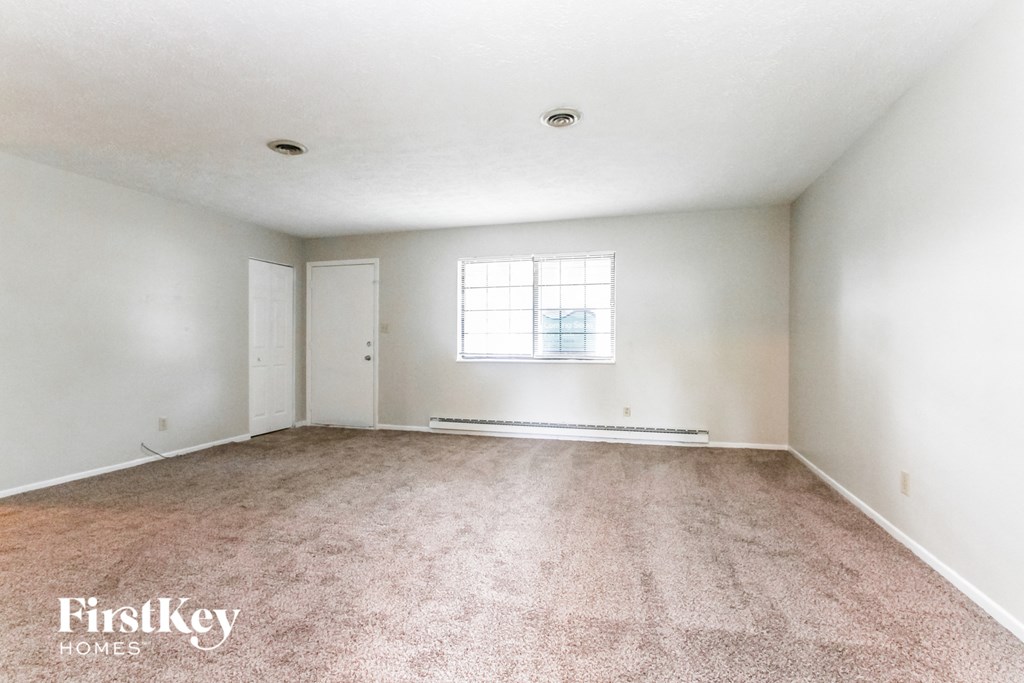 an empty living room with carpet and a window
