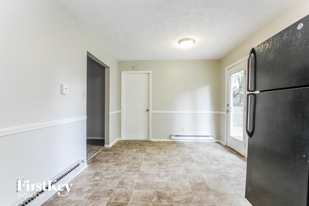 a kitchen with white walls and a refrigerator and a door