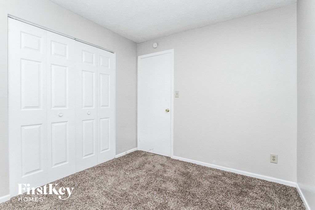 a bedroom with white walls and carpet and white doors